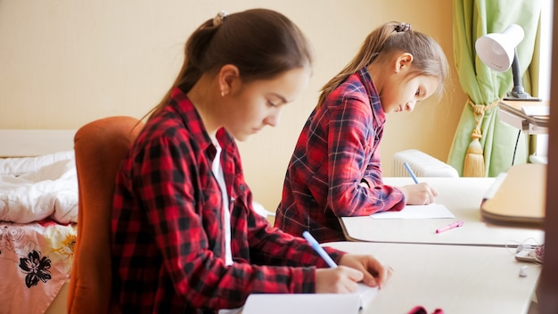 Porträt von zwei Mädchen im Teenageralter, die wegen Quarantäne und Covid-19 zu Hause studieren.