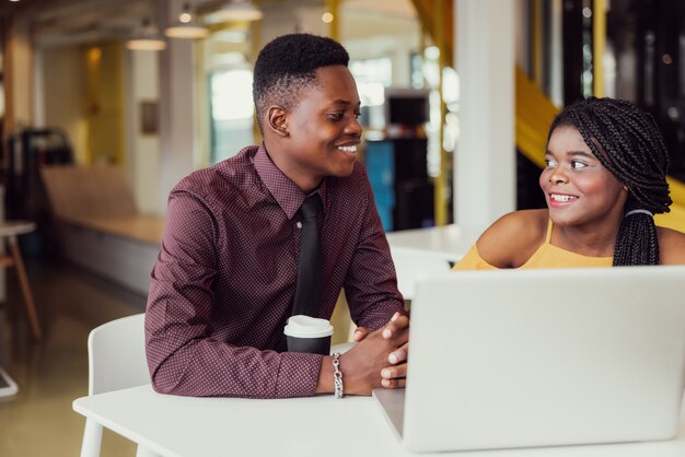 Porträt von zwei schwarzen Studenten mit Netbook, die zu Hause sitzen, Afroamerikaner, der Laptop-Computer verwendet, um Informationen zu suchen und Buchungen vorzunehmen