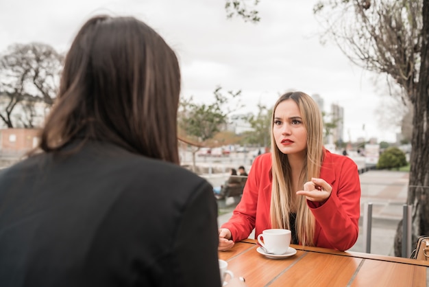 Foto porträt von zwei wütenden freunden, die ein ernstes gespräch führen und diskutieren, während sie im café sitzen. freundschaftskonzept.