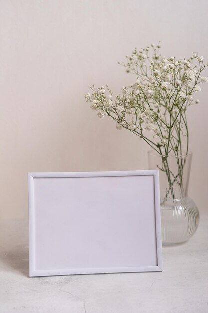 Porträt weißer Bilderrahmen Mockup auf Holztisch Moderne Keramikvase mit Gypsophila