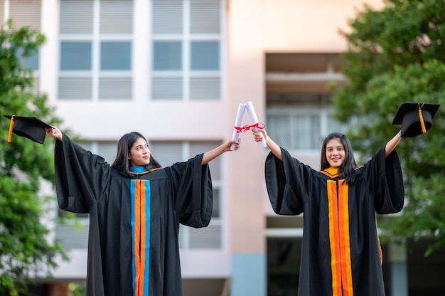 Porträt Zwei Absolventinnen, Hochschulabsolventen mit Diplom und glücklich
