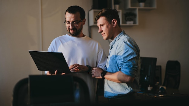 Porträt zweier professioneller männlicher Programmierer, die in verschiedenen Büros am Computer arbeiten. Moderne IT-Technologien, Entwicklung von Programmanwendungen für künstliche Intelligenz und Konzept für Videospiele