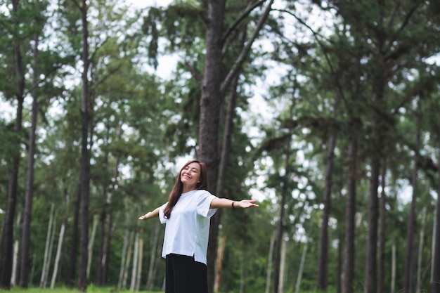 Porträtbild einer glücklichen jungen asiatischen Frau mit sich öffnenden Armen im Park