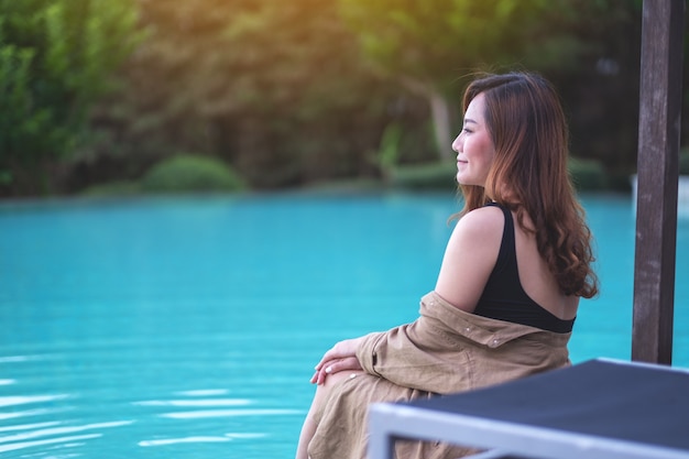 Porträtbild einer schönen asiatischen Frau genoss das Sitzen am Schwimmbad