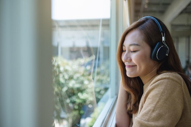 Porträtbild einer schönen jungen asiatischen frau, die gerne musik mit kopfhörern hört