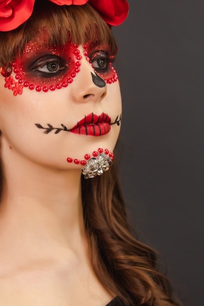 Porträtdetail eines schönen Mädchens mit Make-up Dia de Los Muertos mit grauem Hintergrund.