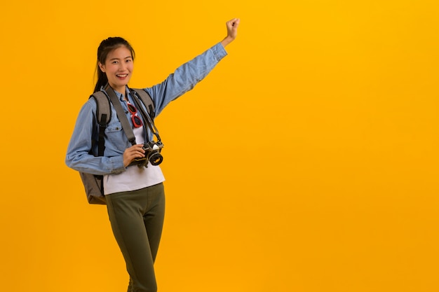 Porträtfoto der jungen attraktiven asiatischen touristischen Frau auf Gelb