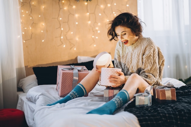 Porträtfrau, die im Bett mit Geschenken herum sitzt