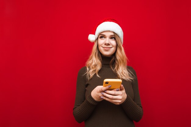 Porträtfrau, die Weihnachtsmütze mit Telefon trägt