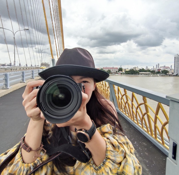 Porträtfrau eines Fotografen, der ihr Gesicht mit einer Kamera bedeckt