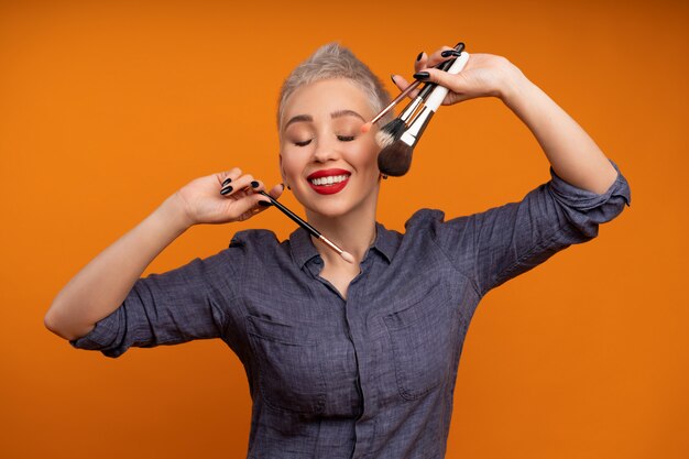 Porträtfrau mit kurzen Haaren mit Make-up-Pinsel in der Hand Studio Shot