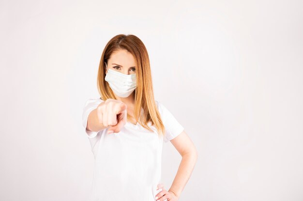 Porträtfrau mit wegwerfendem Gesichtsmaskenzeigefinger vorne lokalisiert auf Weiß
