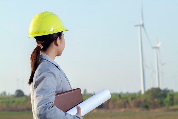 Porträtfrauen-Asieningenieur, der Pläne am Windturbinenbauernhof bearbeitet und hält