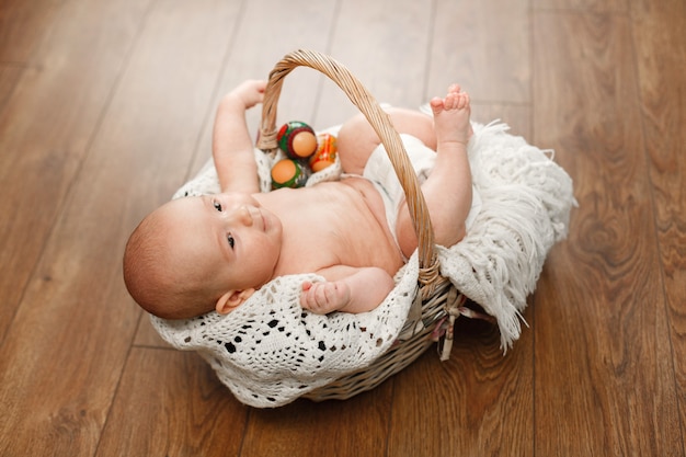 Porträtieren Sie einen niedlichen Jungen in Weidenkorb Ostern. kleines neugeborenes Baby im Weidenkorb auf Holzwand. lächelndes Kind und Ostereier