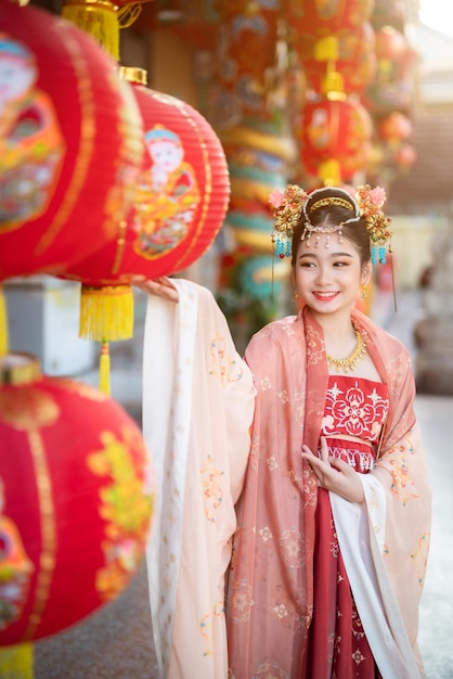 Porträtlächeln Nettes kleines asiatisches Mädchen, das chinesische Kostüme trägt, Dekoration für das chinesische Neujahrsfest, feiert die Kultur Chinas am chinesischen Schrein Öffentliche Orte in Thailand