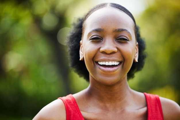 Porträtlächeln und schwarze Frau im Park im Freien und im Garten mit natürlichem Selbstvertrauen, guter Laune und Freiheit in Nigeria. Sie stehen einer glücklichen afrikanischen Frau gegenüber und lachen im Sommer oder entspannen sich in der Natur