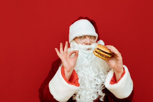 Porträtmann verkleidet als Weihnachtsmann, der Burger hält