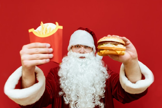 Porträtmann verkleidet als Weihnachtsmann, der Burger und Pommes hält