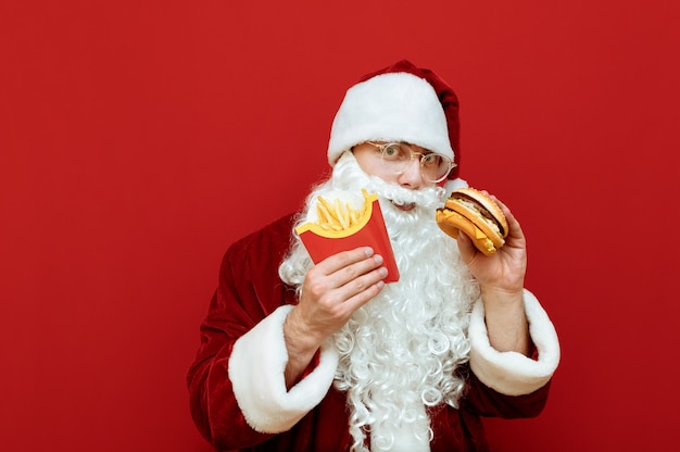 Porträtmann verkleidet als Weihnachtsmann, der Burger und Pommes hält