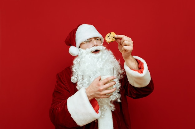 Porträtmann verkleidet als Weihnachtsmann, der Glas Milch und Teller mit Schokoladenplätzchen hält