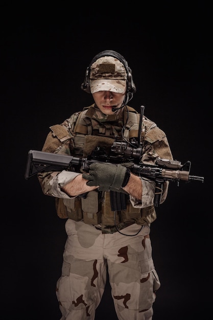 Porträtsoldat oder privater Militärunternehmer, der Scharfschützengewehr-Kriegsarmee-Waffentechnologie und Personenkonzept hält Bild auf schwarzem Hintergrund