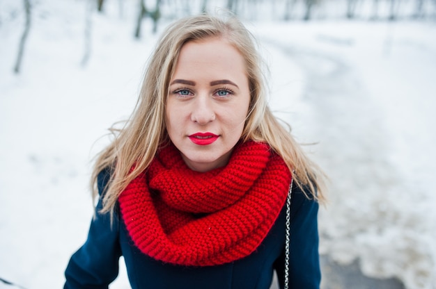Portrai de menina loira no lenço vermelho e casaco em dia de inverno.
