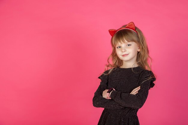 Portrait 6-7 Jahre altes Mädchen im schwarzen Kleid auf rosa isoliert