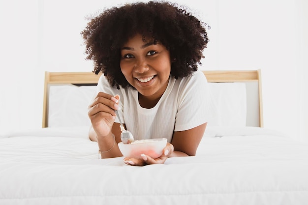 Portrait afroamerikanische Frau, die vor dem Schlafengehen leckere Snacks genießt und sich nicht um die Gesundheit kümmert