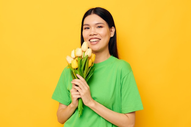 Portrait asiatische schöne junge Frau posiert mit einem Blumenstrauß gelben Hintergrund unverändert