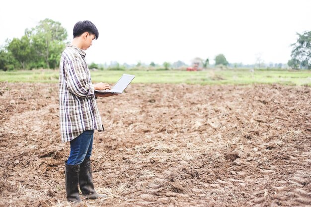 Portrait asiatischer Bauer mit digitalem Laptop auf dem landwirtschaftlichen Reisfeld am Morgen