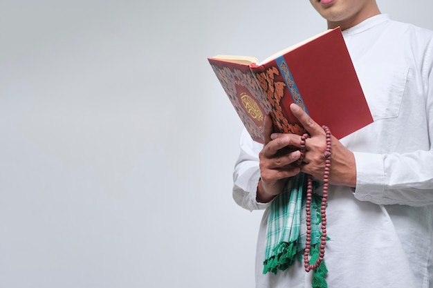 Foto portrait asiatischer muslimischer mann steht und liest den koran isoliert auf weißem hintergrund