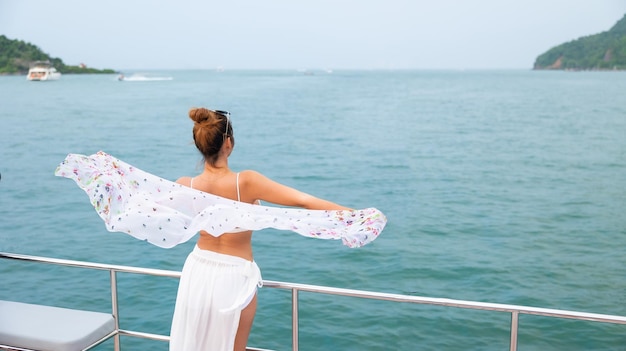 Portrait Attraktiv Fröhliche, schöne, sexy asiatische Frau, die Badebekleidung trägt, die auf dem Bootsdeck genießt, das eine Luxusyacht segelt Urlaubsreise Sommerurlaub