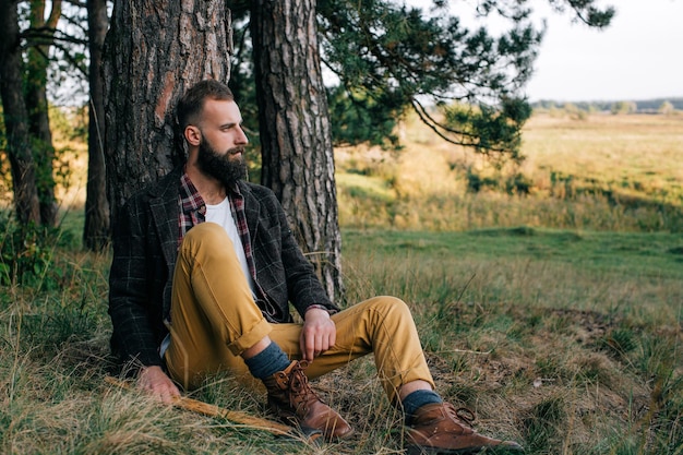 Portrait brutaler bärtiger Hipster-Mann im Wald mit Axt