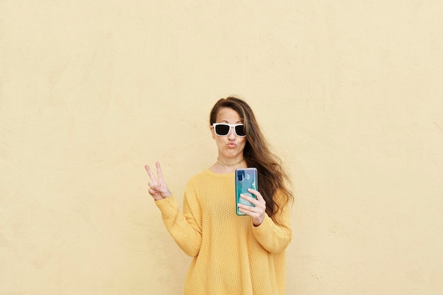 Portrait cooles Mädchen mit Sonnenbrille, das einen süßen Luftkuss mit dem Telefon sendet