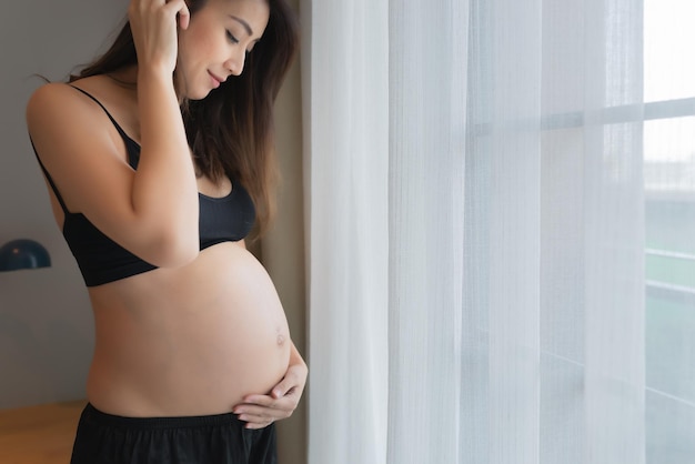 Portrait der asiatischen schwangeren Frau im Schlafzimmer