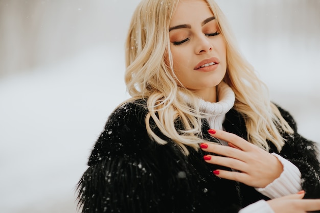 Portrait der blonden Frau draußen im Schneewintermantel
