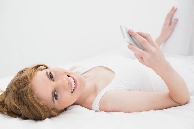 Portrait der entspannten Frau mit Handy im Bett