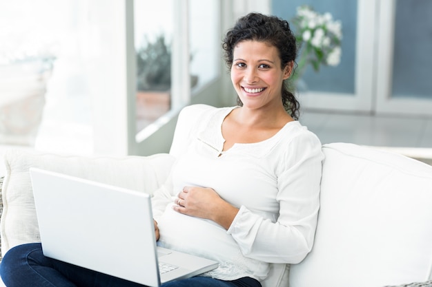 Portrait der glücklichen Frau, die Laptop auf Sofa verwendet