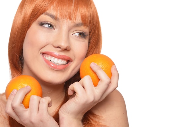 Portrait der jungen Frau, die mit Orangen auf weißem Hintergrund aufwirft