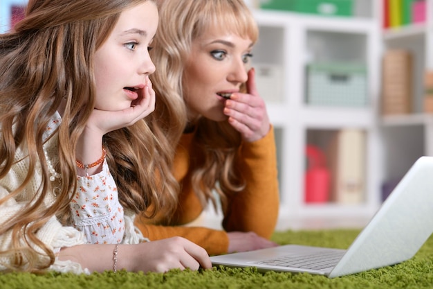 Portrait der jungen Frau mit dem Mädchen, das Laptop verwendet