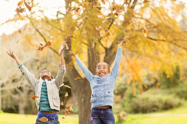 Portrait der jungen Kinder, die herum Blätter werfen