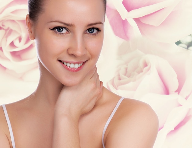 Portrait der jungen schönen Frau mit gesunder Haut. Rosen Hintergrund