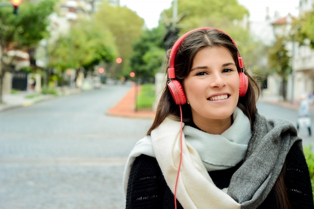 Portrait der jungen schönen Frau mit hörender Musik der roten Kopfhörer