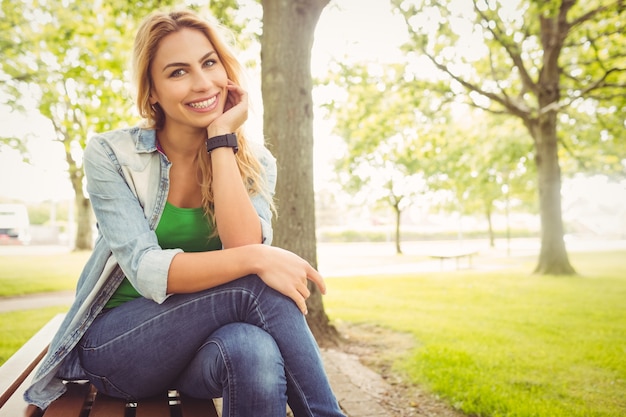 Portrait der lächelnden Frau mit der Hand auf Kinn am Park