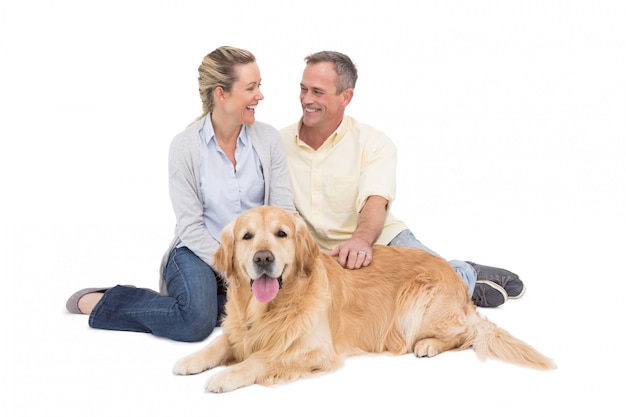 Portrait der lächelnden Paare, die zusammen mit ihrem Hund sitzen