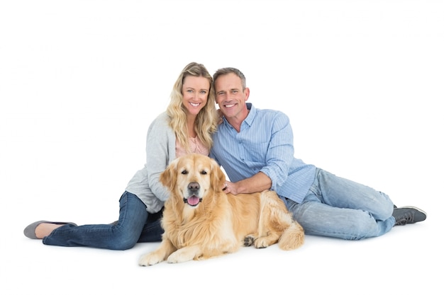 Portrait der lächelnden Paare, die zusammen mit ihrem Hund sitzen