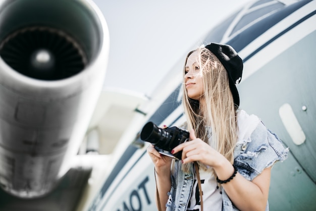 Portrait der schönen touristischen Frau mit alten Film Vintage Kamera posiert in der Nähe des Flugzeugs