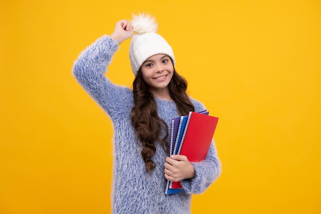 Portrait der Schule Teenager-Mädchen im Herbst Hut mit Heften und Rucksack über gelbem Hintergrund Herbstschule Glückliches Schulmädchen, positive und lächelnde Emotionen