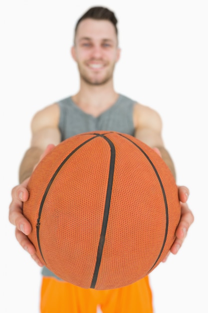 Portrait des glücklichen jungen Mannes, der Basketball anhält