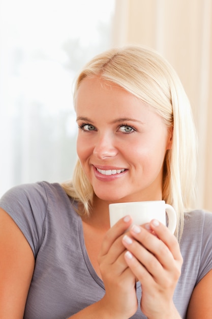 Portrait einer Frau, die auf einer Couch mit einem Tasse Kaffee sitzt